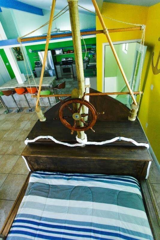 A bed in the shape of a boat with a steering wheel