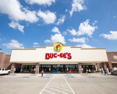 The front of a buc-ee 's grocery store with a parking lot in front of it.