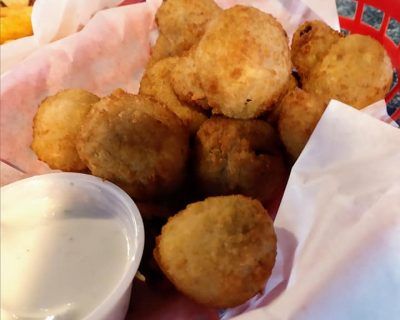 A basket of fried mushrooms next to a container of dipping sauce