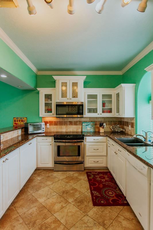 A kitchen with green walls and white cabinets and a stove.