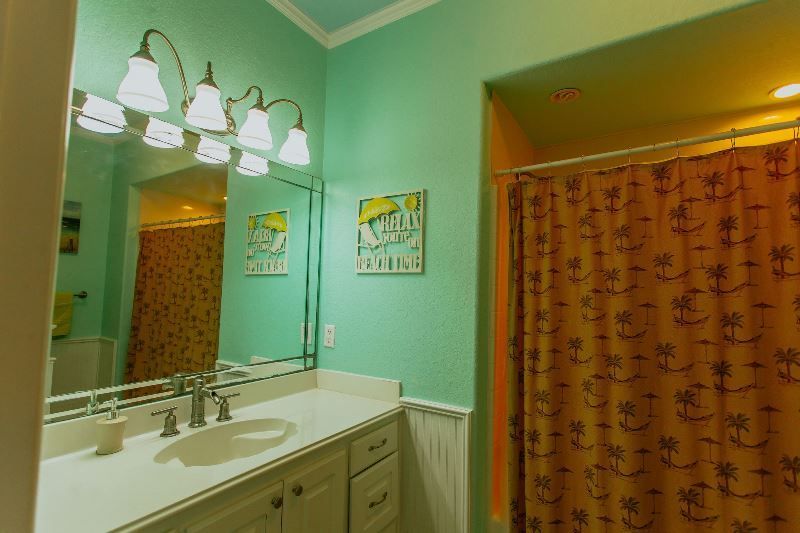 A bathroom with a sink , mirror and shower curtain.