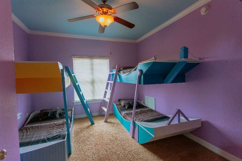 A bedroom with three bunk beds and a ceiling fan.