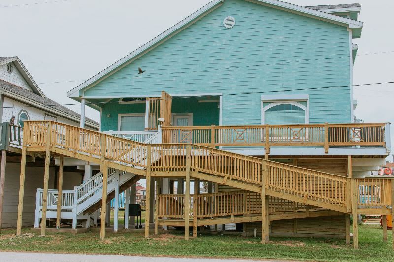 A blue house with a wooden deck and stairs.