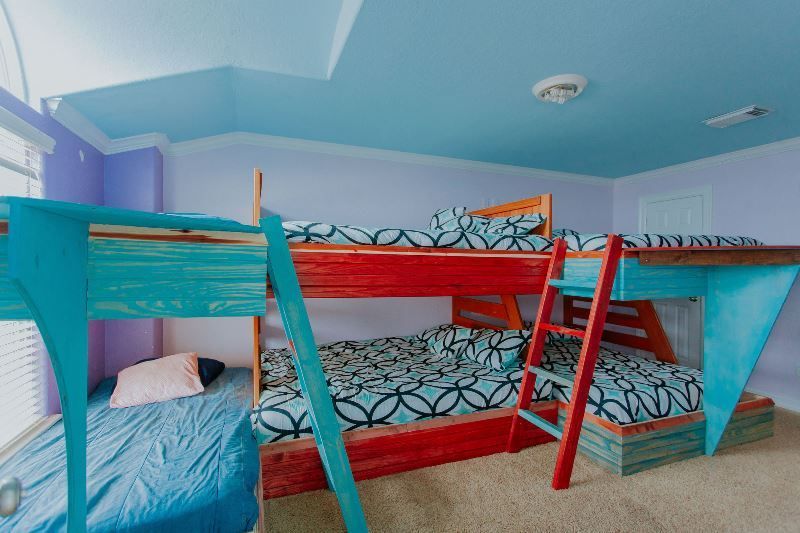 A bedroom with three bunk beds and a blue ceiling.