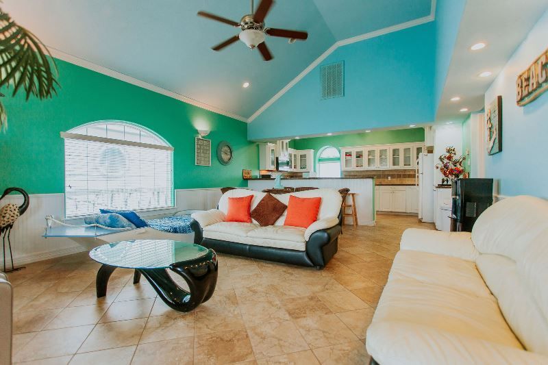 A living room with a couch , table , and ceiling fan.