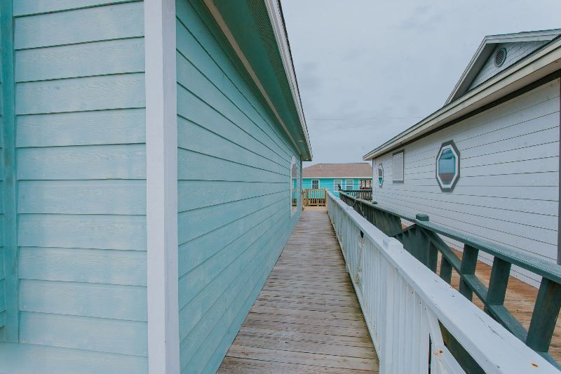 A wooden walkway between two blue and white houses