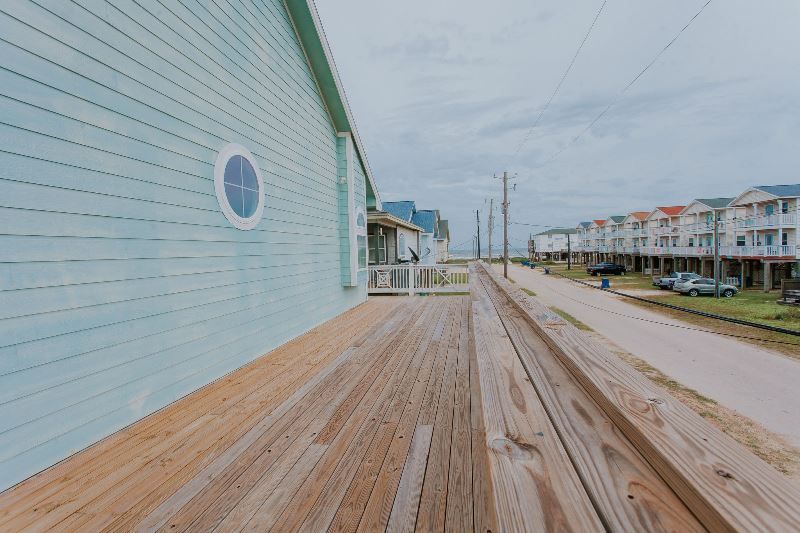 A wooden deck leading to a building with a clock on the side of it.