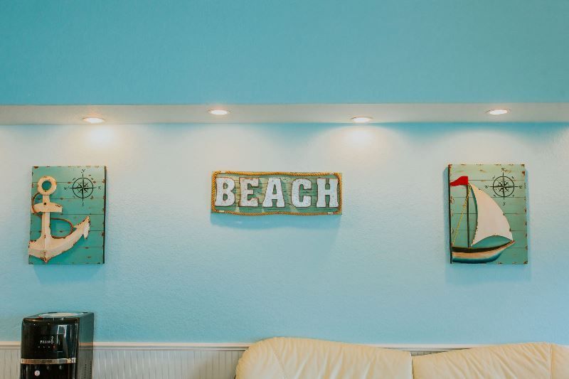 A living room with a couch and a sign on the wall that says beach.