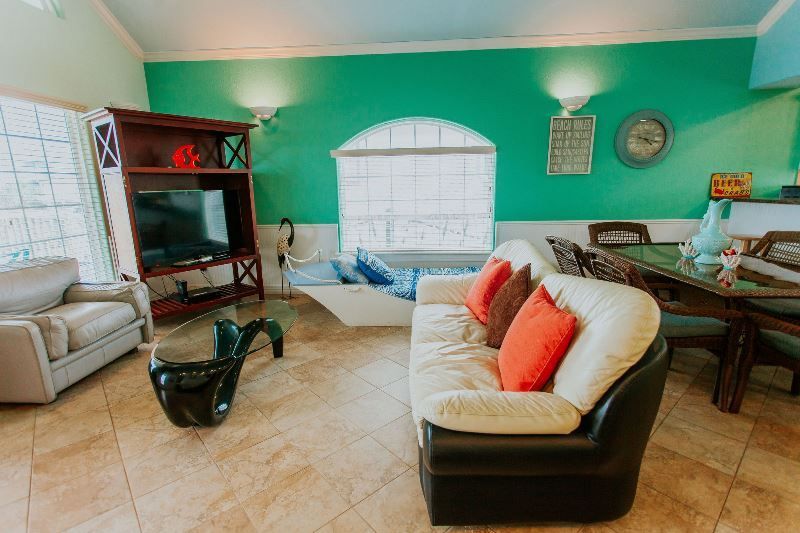 A living room with a couch , chairs , table and television.