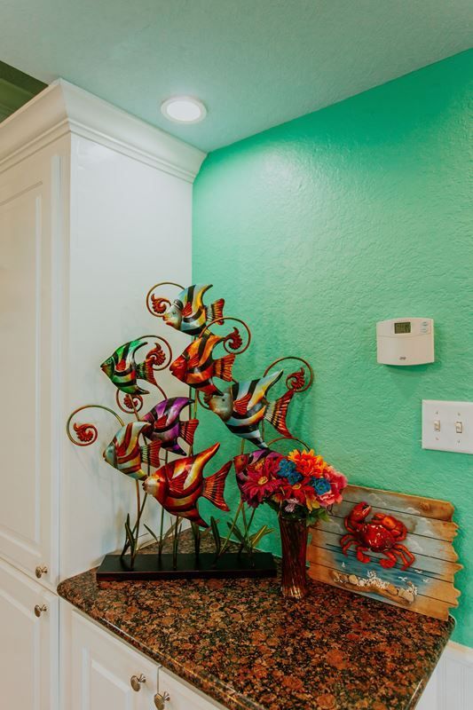 A kitchen counter with a vase of flowers and a statue of fish on it.