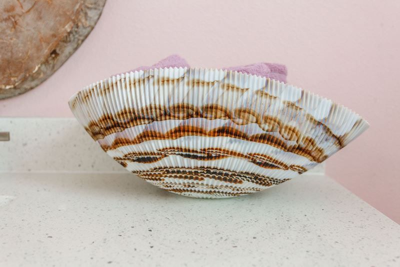 A bowl is sitting on a counter next to a pink wall.