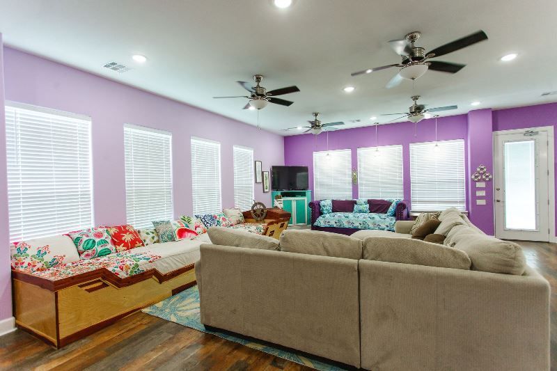 A living room with a lot of furniture and a purple wall.
