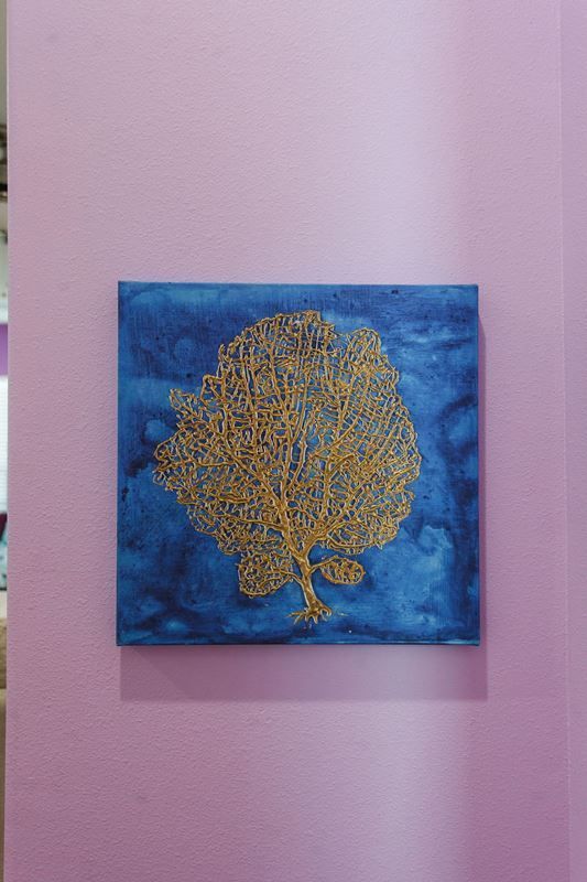 A blue and gold painting of a tree on a pink wall.
