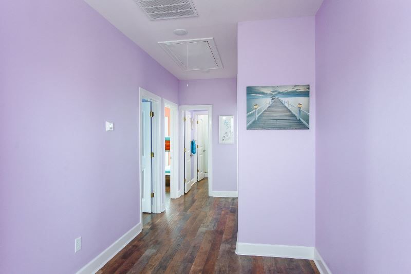 A hallway with purple walls and a painting on the wall.