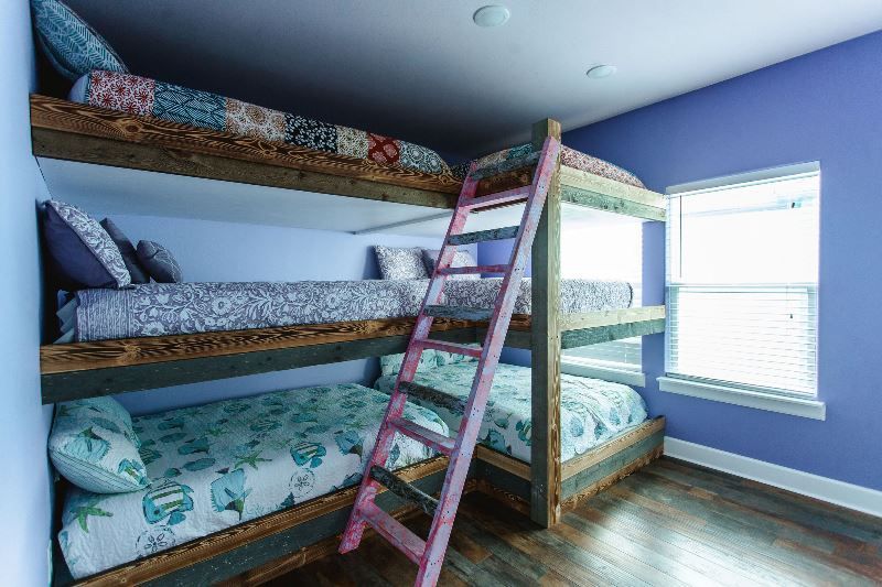 A bedroom with three bunk beds and a pink ladder.