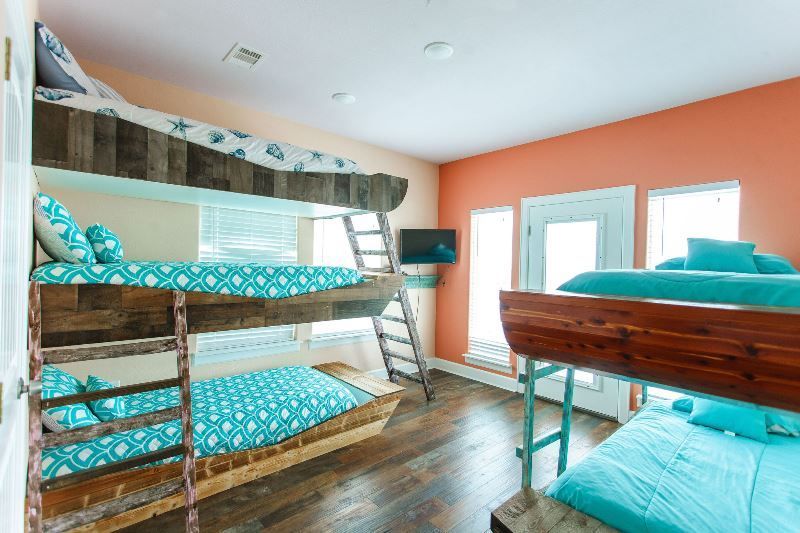 A bedroom with three bunk beds and a television.