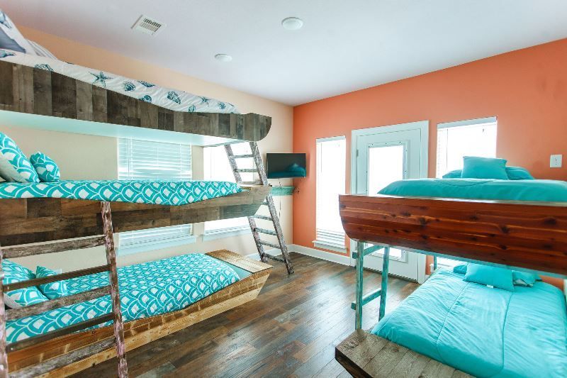 A bedroom with bunk beds and a television on the wall.