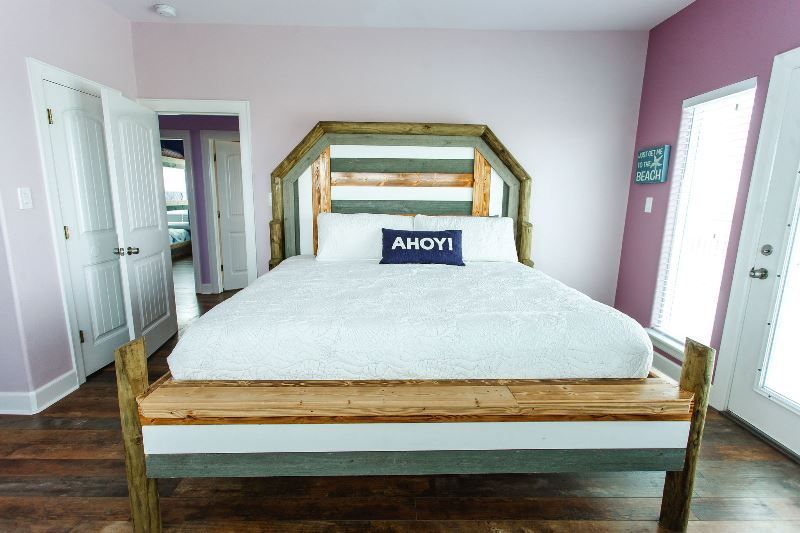 A bedroom with a bed and a pillow that says ahoy.