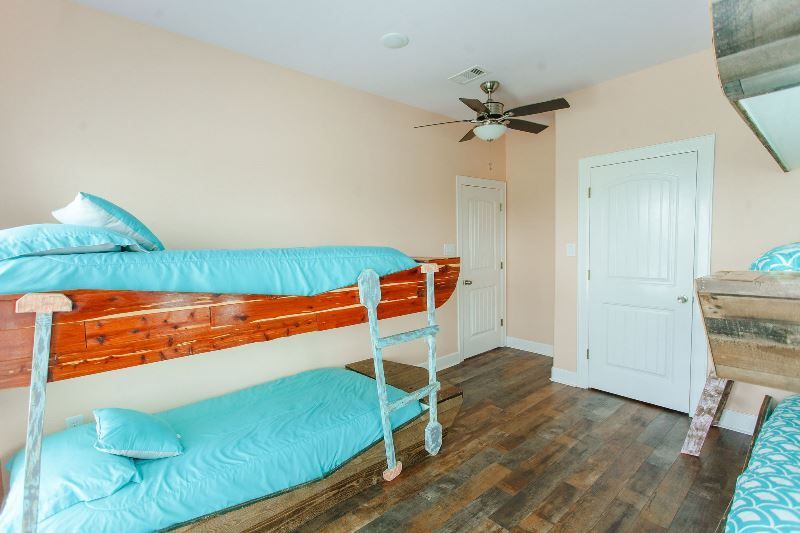 A bedroom with two bunk beds and a ceiling fan.