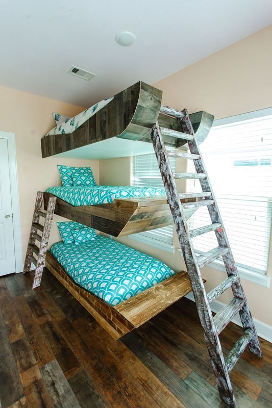 A bedroom with three bunk beds and a ladder.