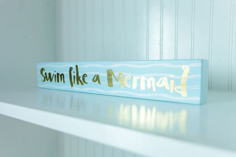 A sign that says `` swim like a mermaid '' is on a shelf.