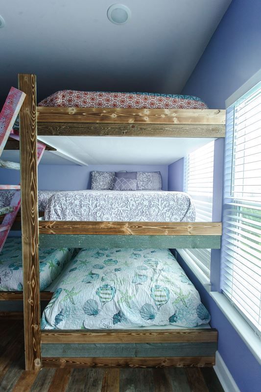 A bedroom with three bunk beds and a window.
