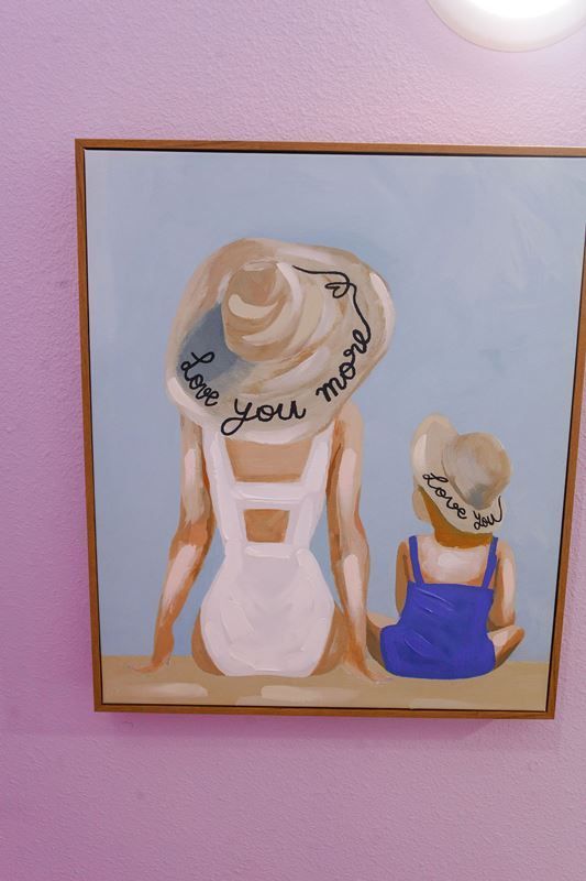 A painting of a mother and daughter sitting on the beach