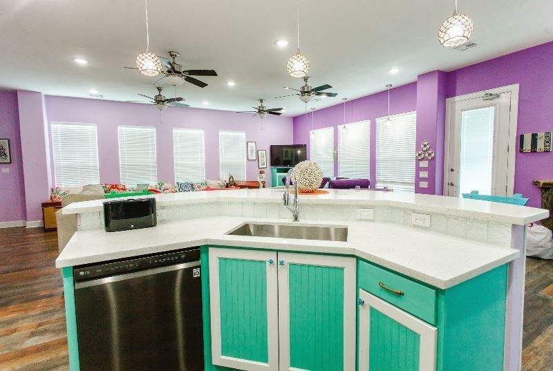 A kitchen with a sink , dishwasher , and purple walls.