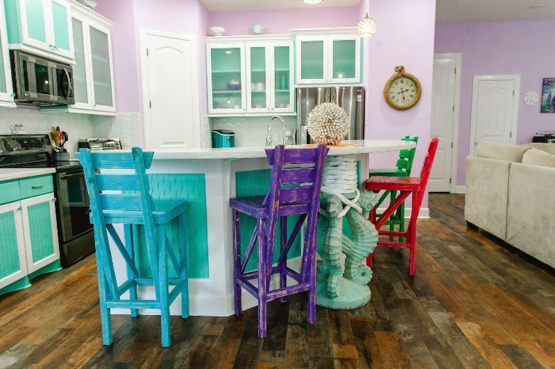 A kitchen with colorful chairs and a clock on the wall.