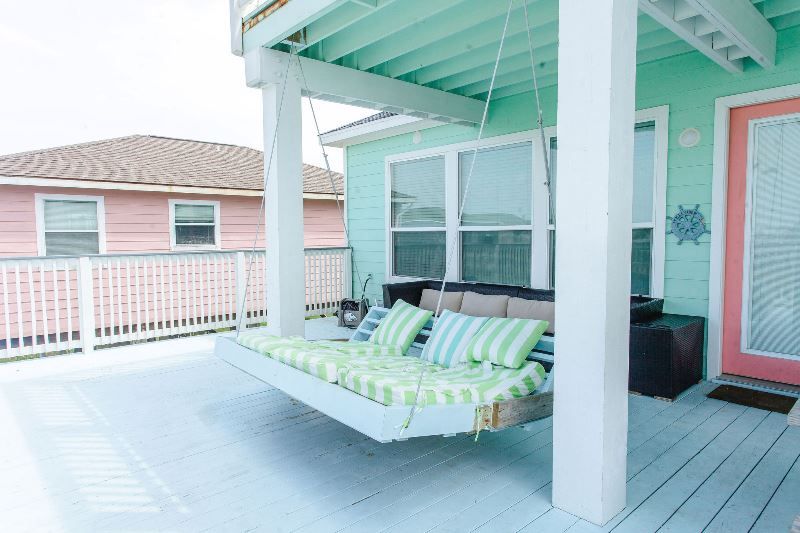 A porch swing is hanging from the ceiling of a house.