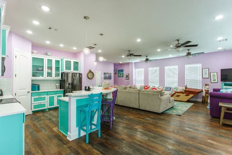 A kitchen , living room , and dining room in a house with purple walls.