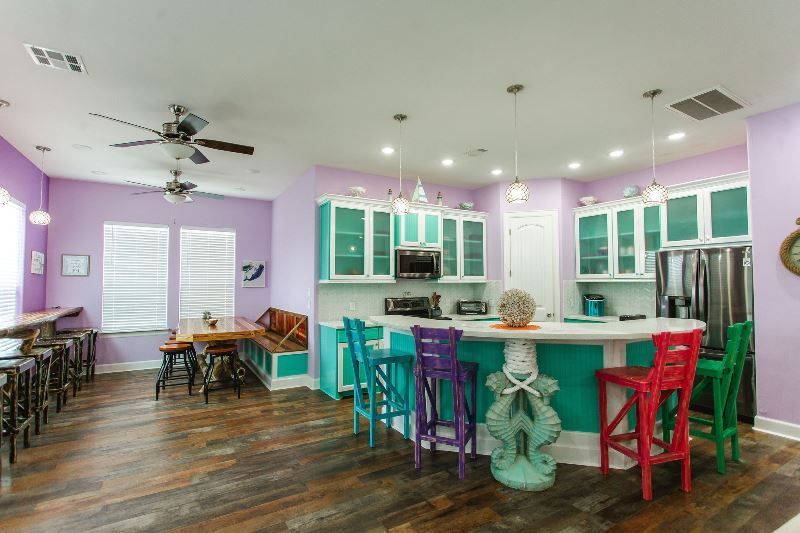 A kitchen with purple walls , green cabinets , and a large island.