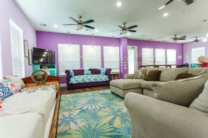 A living room with purple walls , a couch , chairs , and a television.