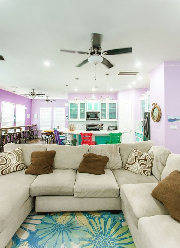 A living room with a large sectional couch and a ceiling fan.