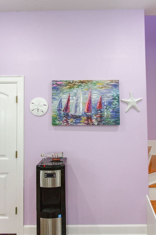 A room with purple walls and a painting of sailboats on the wall.