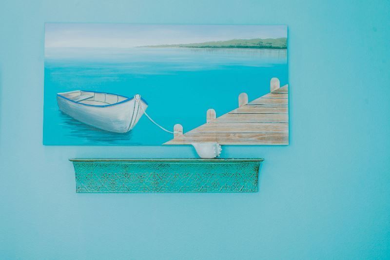 A painting of a boat tied to a dock on a blue wall.