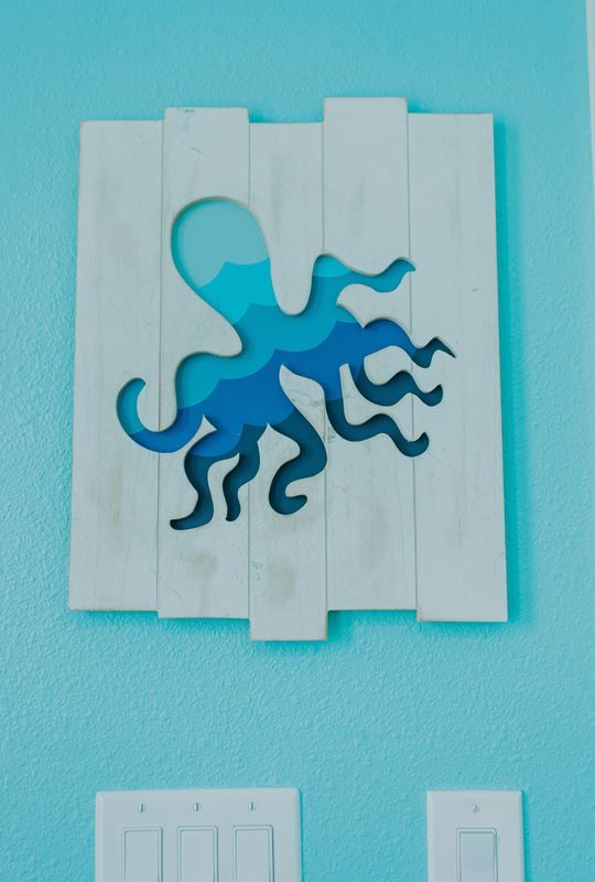 A picture of an octopus is hanging on a blue wall.