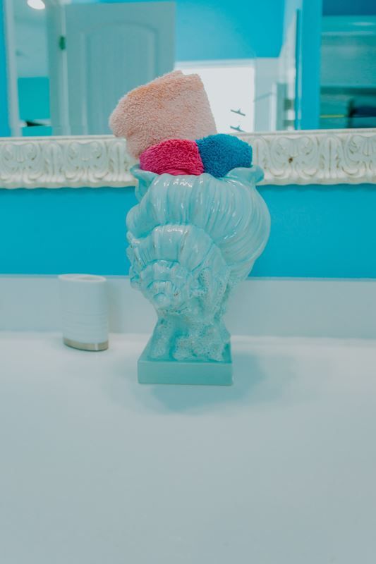 A vase filled with towels and sponges is sitting on a bathroom counter.