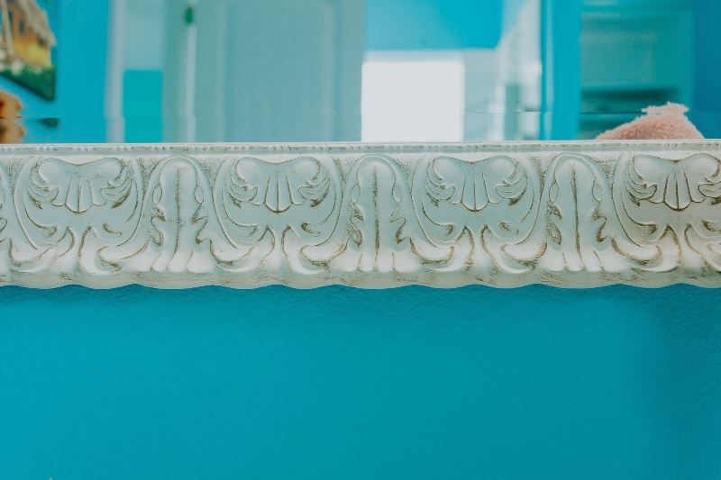 A close up of a mirror with a white frame on a blue wall.