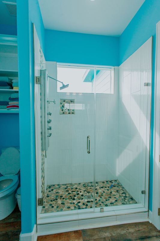 A bathroom with blue walls and a walk in shower