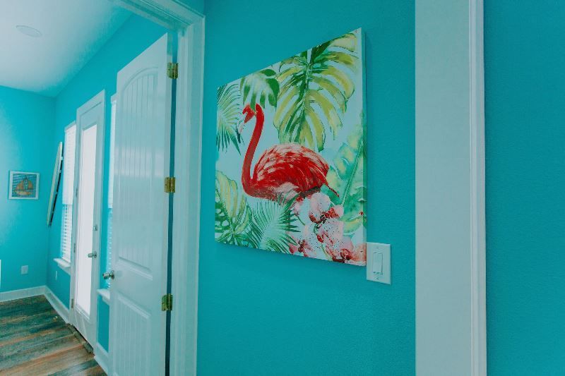 A hallway with blue walls and a painting of a flamingo on the wall.