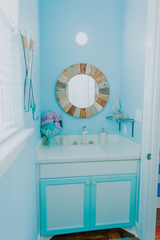 A bathroom with blue walls , a sink and a mirror.