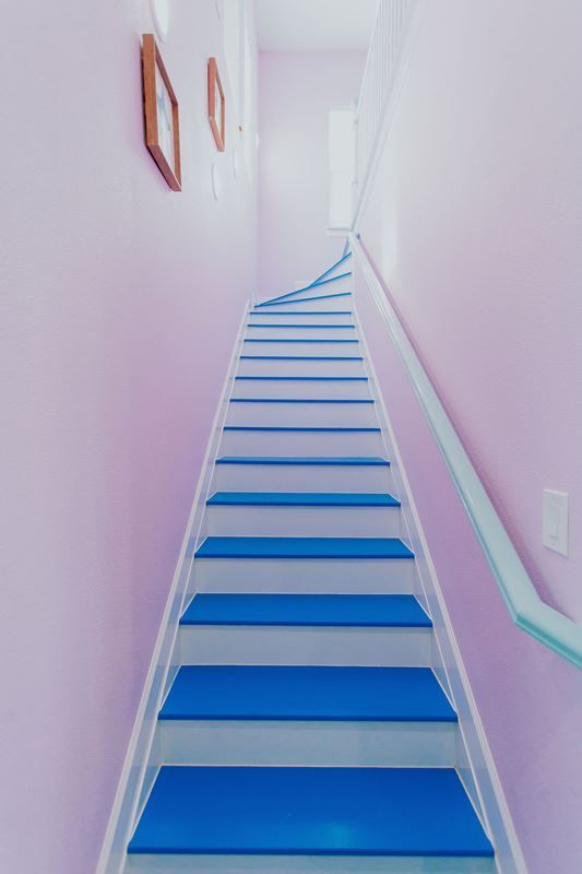 A staircase with blue steps and a white railing in a hallway.