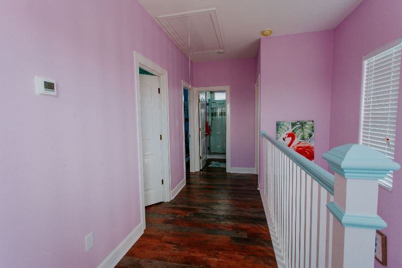 A hallway with pink walls and wooden floors in a house.
