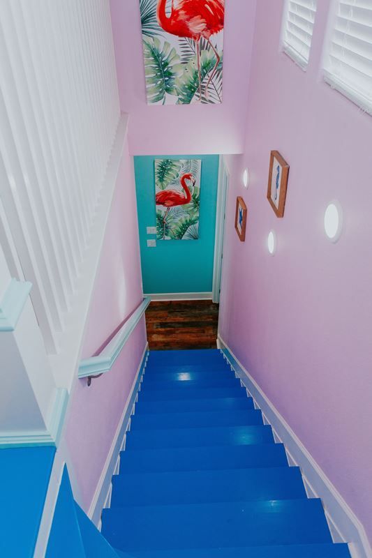 A blue and pink staircase with a flamingo painting on the wall.