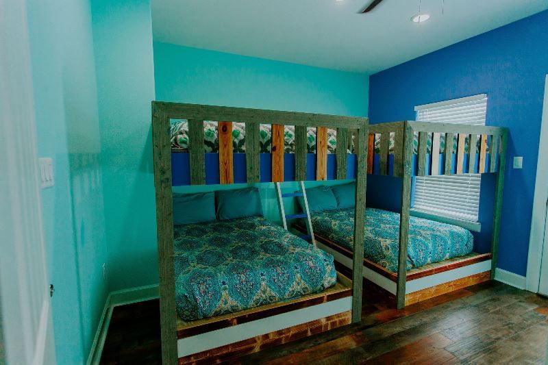 A bedroom with three bunk beds and blue walls.