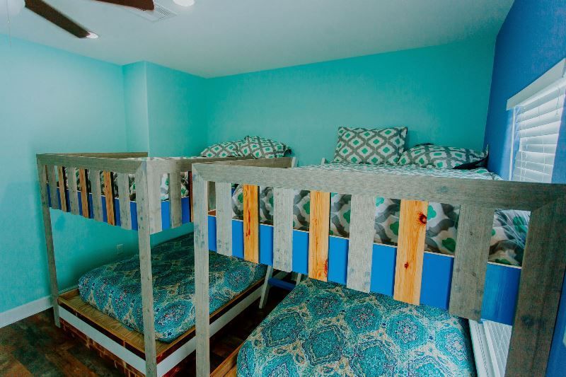 A bedroom with three bunk beds and a ceiling fan.