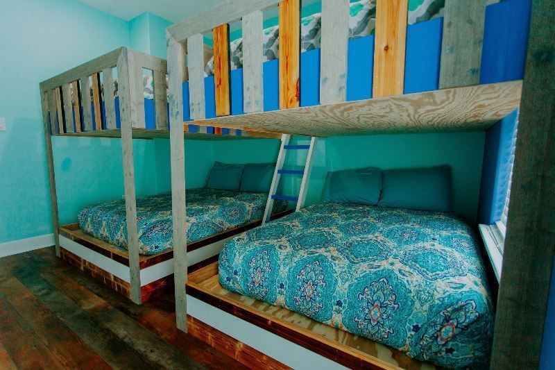 There are three bunk beds in a room with blue walls.