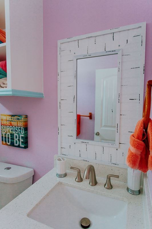 A bathroom with pink walls a sink and a mirror