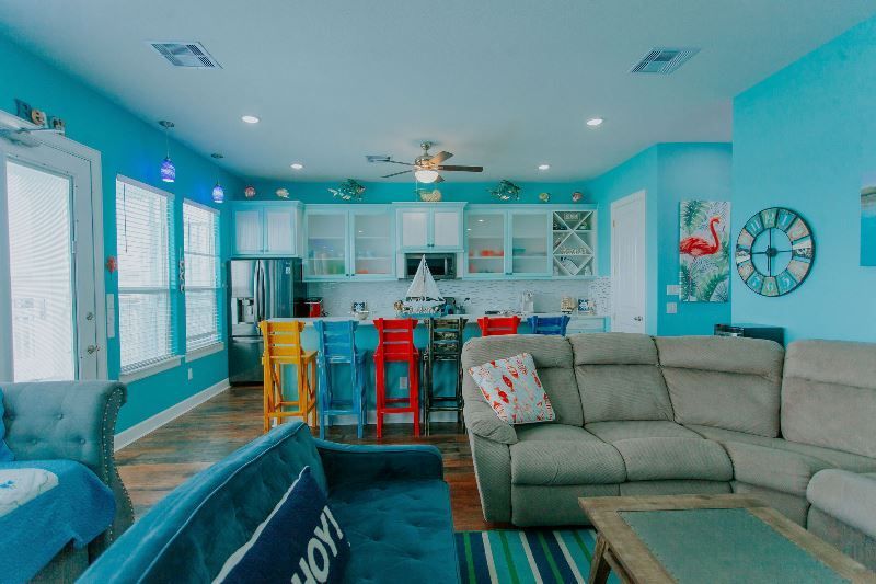 A living room with blue walls , a couch , a coffee table , and a kitchen.